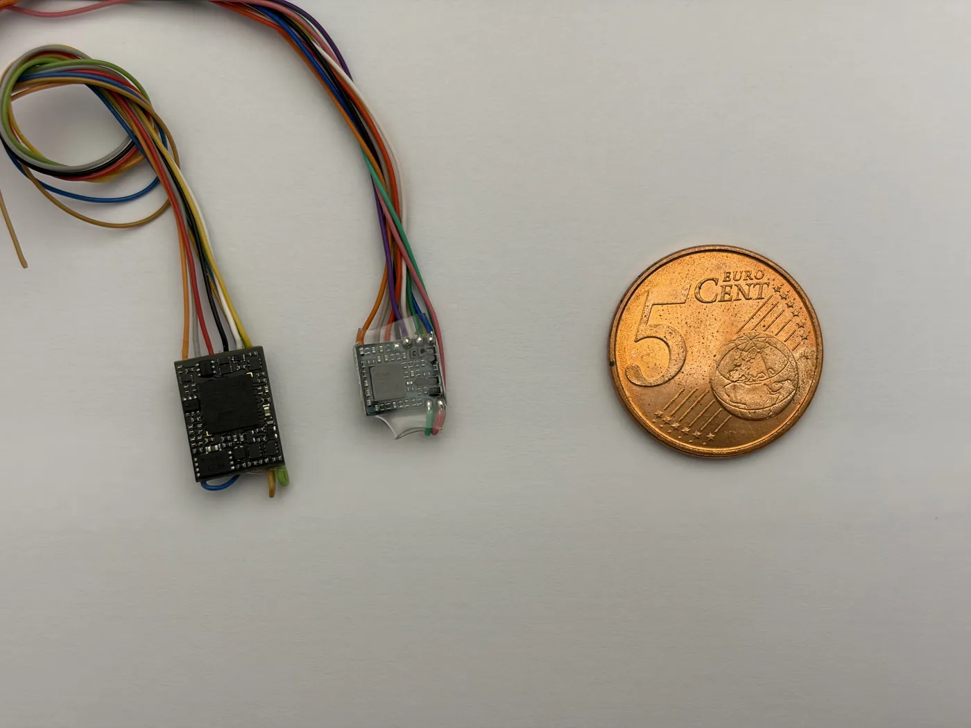 Größenvergleich zweier Spur-N-Decoder – Zimo MN170 (links) und ESU LokPilot 5 micro (rechts) – neben einer 5-Cent-Münze
