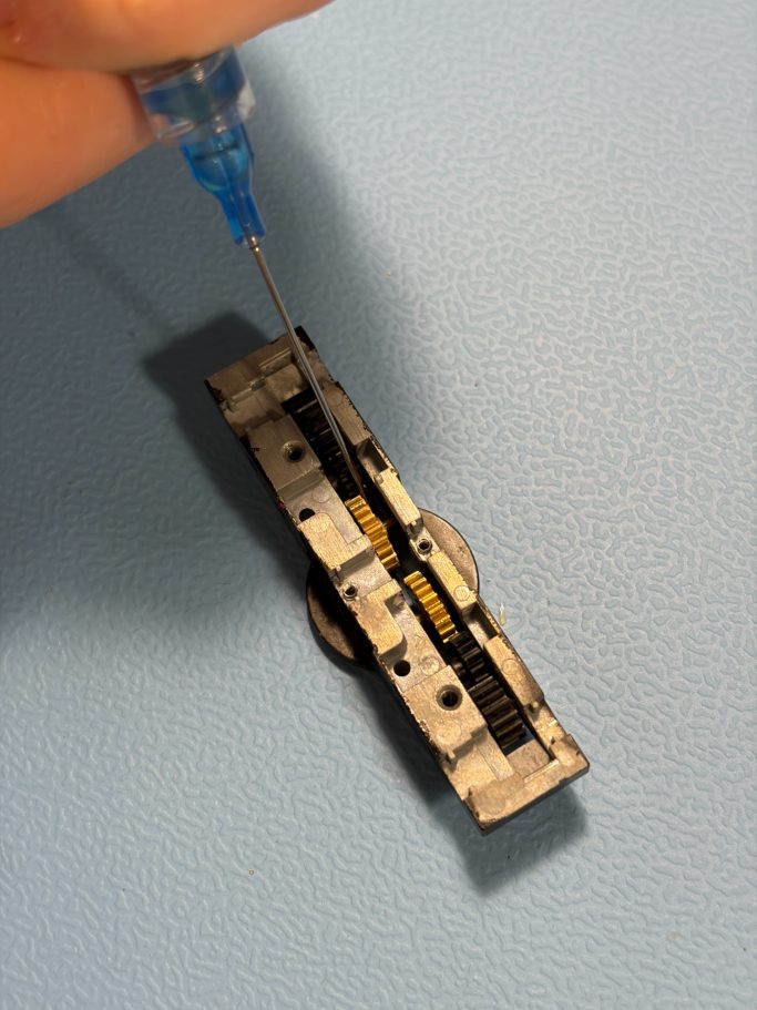 Getriebe einer Lokomotive welches mithilfe einer Spritze frisch geschmiert wird.