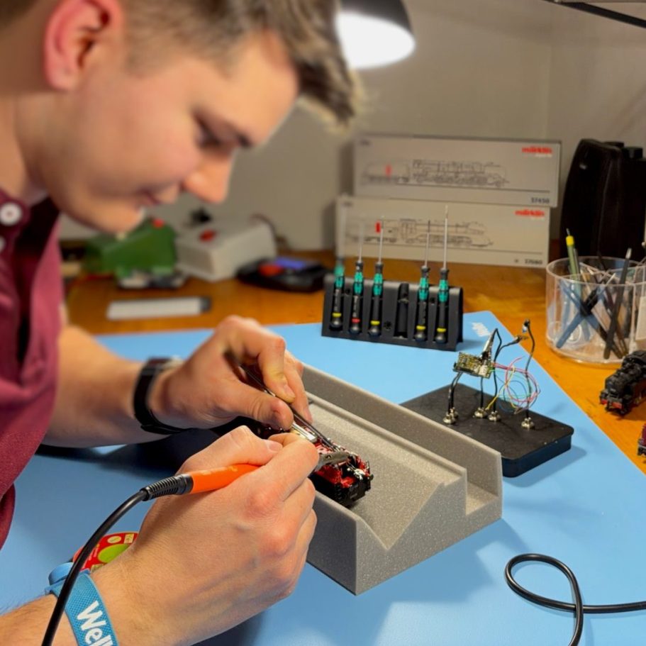 Mann arbeitet an einer LGB Lok in einer Werkstatt, Werkzeug um ihn herum.