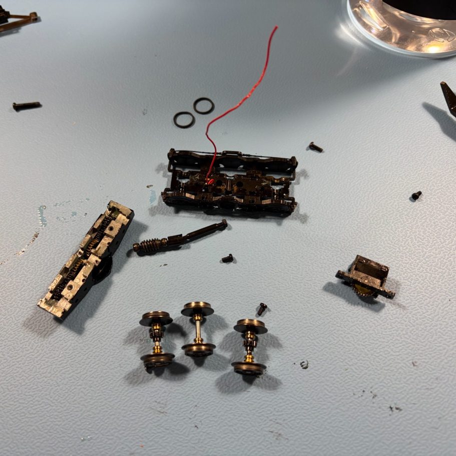 Detailaufnahme einer alten Modelleisenbahn Lok mit glänzenden Rädern und einem bronzefarbenen Schleifer.